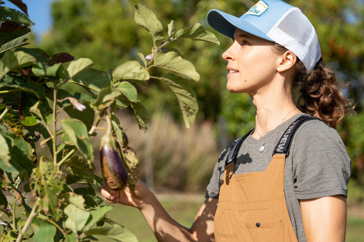Woman gardening outdoors on a sunny day wearing a Dermatone hat