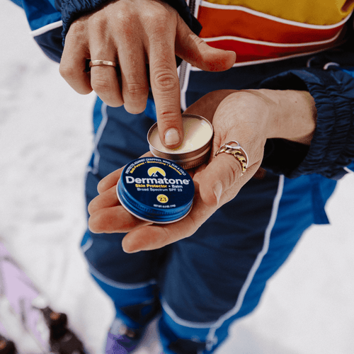 an up close shot of Dermatone's skin protector balm in someones hand with a finger in the clear balm