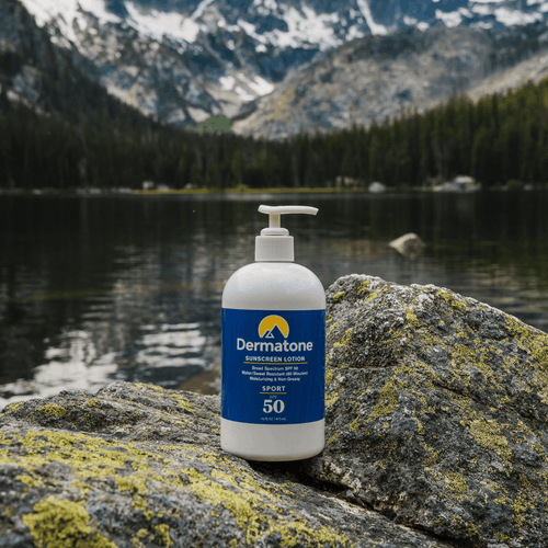 sunscreen bottle with pump sitting on a rock in front of an alpine lake